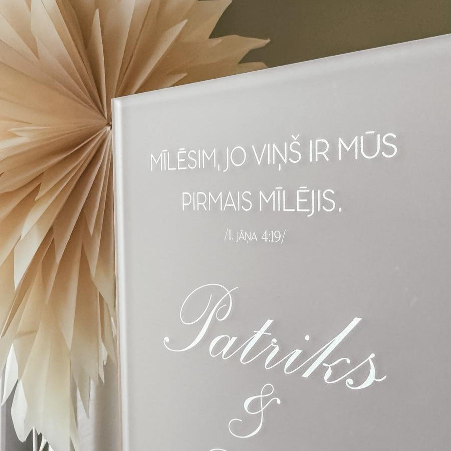 "MĪLĒSIM, JO VIŅŠ MŪS PIRMAIS IR MĪLĒJIS" STIKLA DEKORS KOKA STATĪVĀ AR BALTIEM ZIEDIEM (Copy)